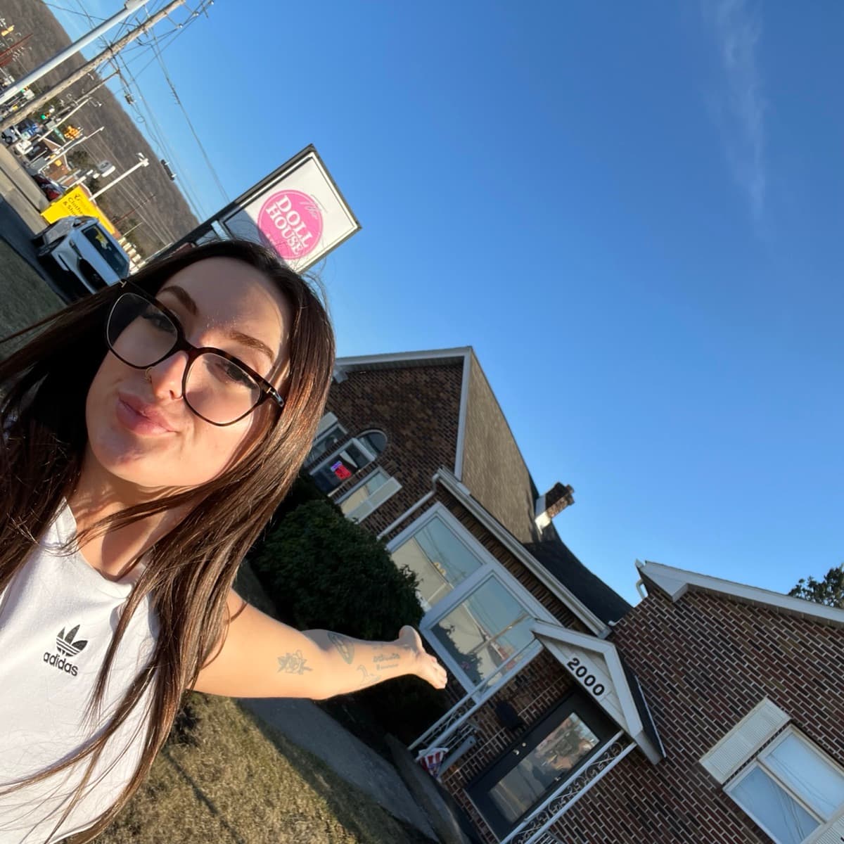 Miranda outside The Dollhouse salon pointing at the shop sign